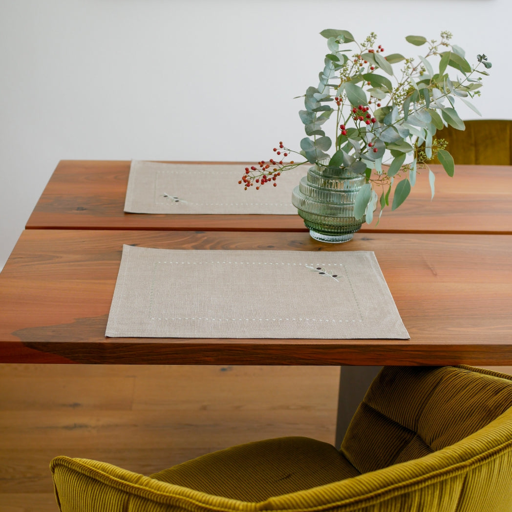 Tischset aus 100 % gewaschenem Leinen in Naturton, verziert mit einem feinen olivfarbenen Stickmuster. Das dezente Design bringt mediterrane Eleganz und handwerkliche Raffinesse auf den gedeckten Tisch.