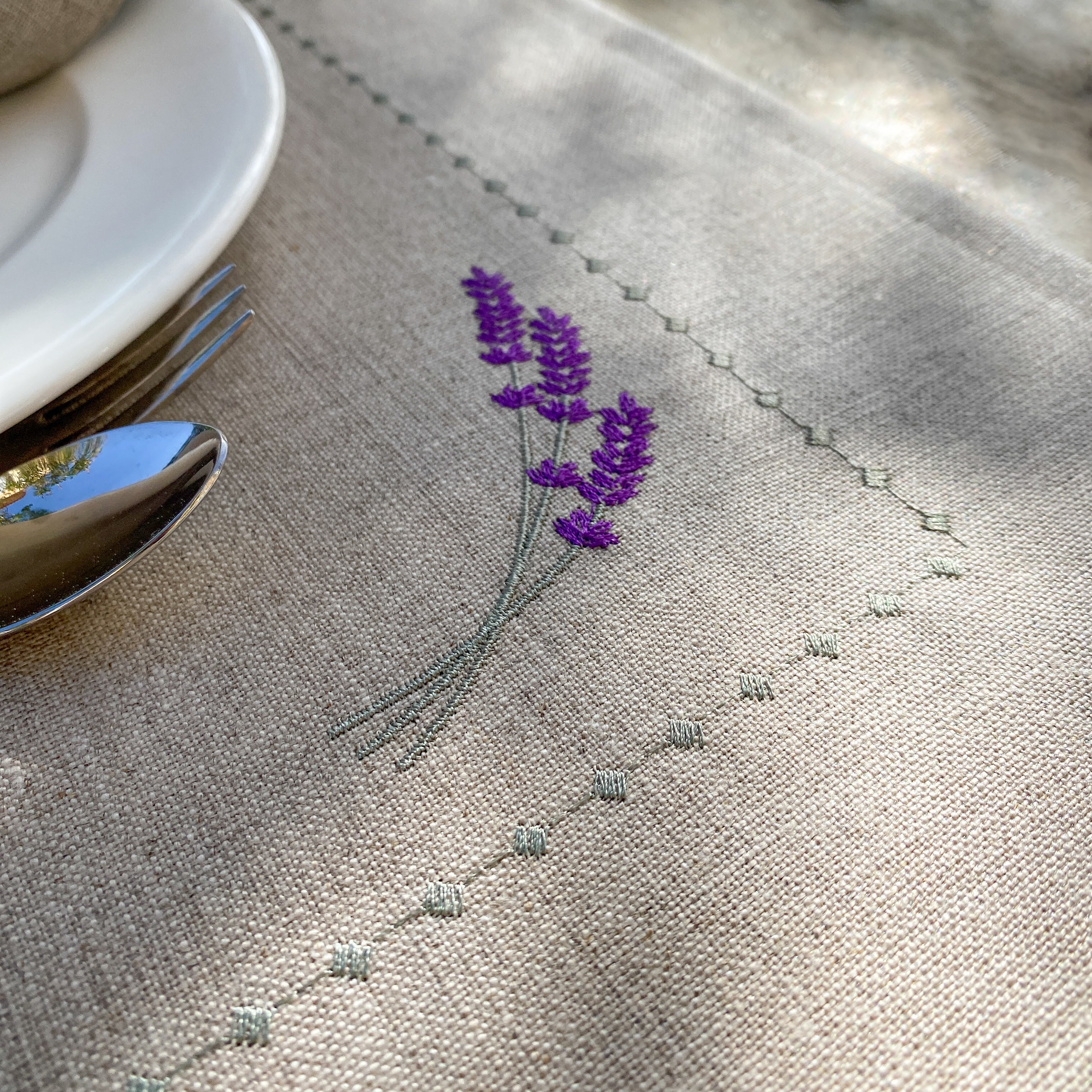 Tischset aus 100 % gewaschenem Leinen in Naturfarbe, verziert mit einer zarten Lavendel-Stickerei in Violetttönen. Das Design verbindet provenzalische Leichtigkeit mit handwerklicher Eleganz – ideal für eine stilvolle Tischdekoration.