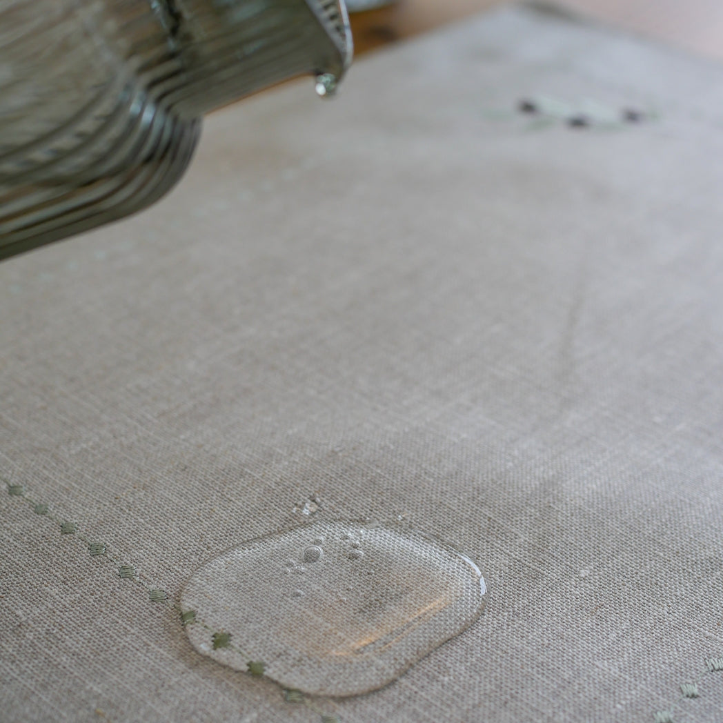Tischset aus 100 % gewaschenem Leinen in Naturton, verziert mit einem feinen olivfarbenen Stickmuster. Das dezente Design bringt mediterrane Eleganz und handwerkliche Raffinesse auf den gedeckten Tisch.