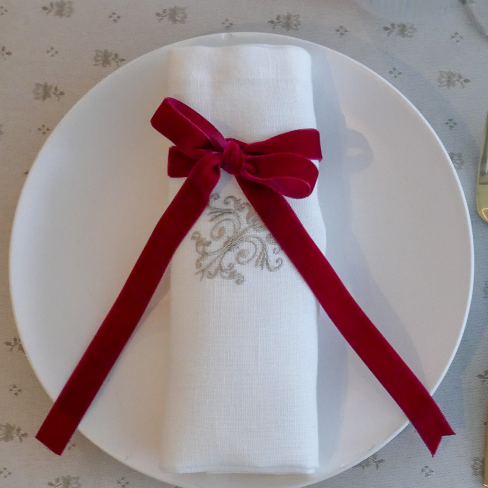 Leinenserviette mit feinem, gesticktem Ornamentmotiv in Naturfarbe, kunstvoll gefertigt in unseren Werkstätten in Südfrankreich. Präsentiert auf einem gedeckten Tisch für einen eleganten, zeitlosen Look.