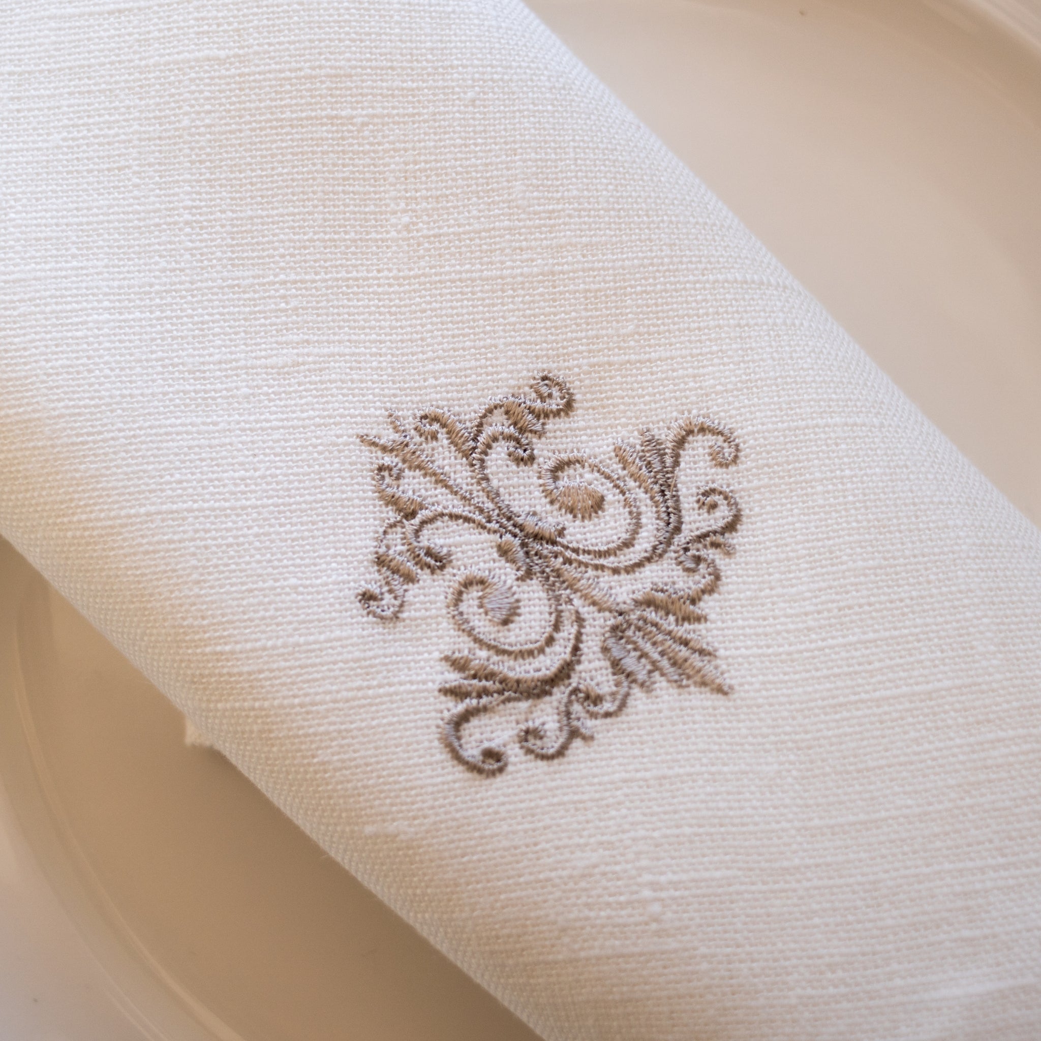 Serviette aus weißem Leinen mit feinem Ornamentmuster – elegant, zeitlos und hochwertig verarbeitet.